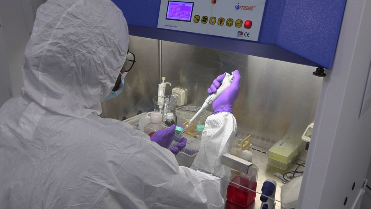 A scientist in protective coveralls working in a biosafety cabinet