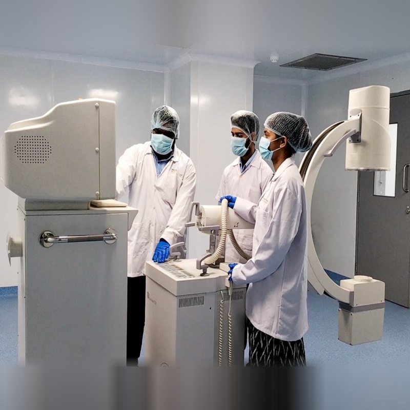 Team working with a C-arm X-ray system in a clean-room lab